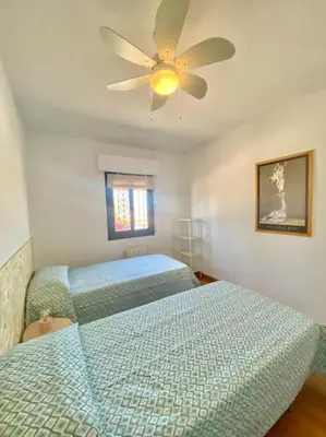 a bedroom with two beds and a ceiling fan at Amplio adosado a pocos metros de la playa in Poblado de Sancti Petri