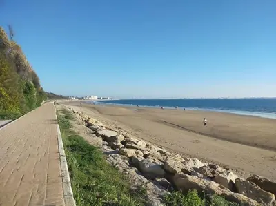 a sandy beach with people walking on it at Apartamento Cata in El Puerto de Santa María