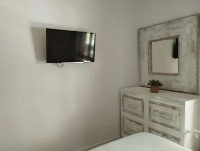 a room with a television on a wall with a dresser at Apartamento Cata in El Puerto de Santa María