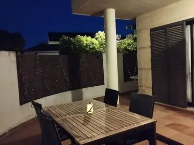 a wooden table and chairs on a balcony at night at Apartamento Cata in El Puerto de Santa María