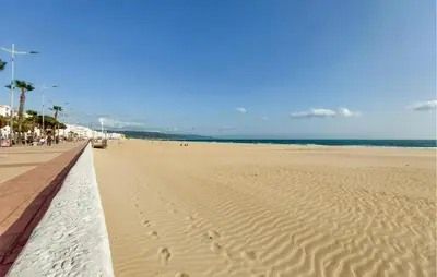 a sandy beach with a pier and the ocean at Nice Home In Chiclana De La Fronter in Novo Sancti Petri
