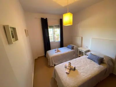 a room with two beds and a light fixture at Apartamento Mirador del Coto in Sanlúcar de Barrameda