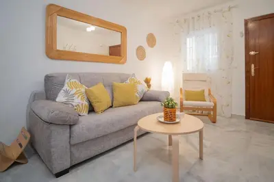 a living room with a gray couch and a mirror at Apartamento Rosole in Sanlúcar de Barrameda