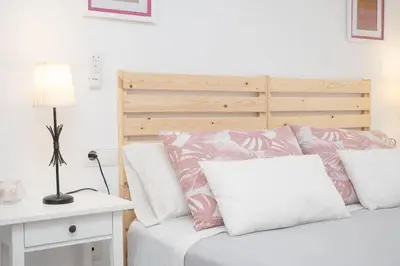 a bedroom with a bed with pink and white pillows at Apartamento Rosole in Sanlúcar de Barrameda