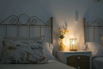 a bedroom with a bed with a vase of flowers and a lamp at Apartamento Rosole in Sanlúcar de Barrameda