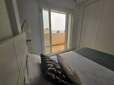 a bedroom with a bed and a large window at Casa en La Barrosa vista mar in Chiclana de la Frontera