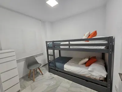 a bedroom with two bunk beds and a chair at Casa en La Barrosa vista mar in Chiclana de la Frontera