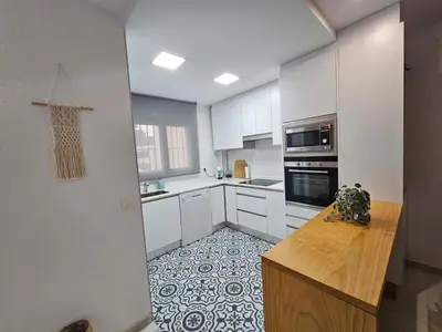 a kitchen with white cabinets and a tile floor at Casa en La Barrosa vista mar in Chiclana de la Frontera