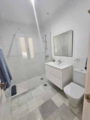 a white bathroom with a toilet and a sink at Casa en La Barrosa vista mar in Chiclana de la Frontera