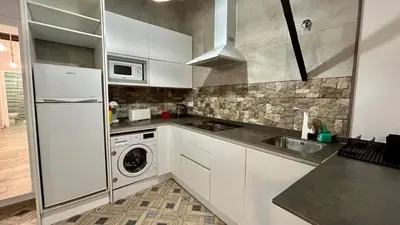 a kitchen with white cabinets and a washer and dryer at Estudio de Mia in Cádiz