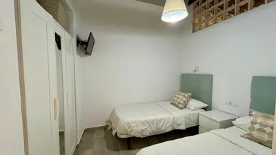 a small bedroom with two beds and a lamp at Estudio de Mia in Cádiz