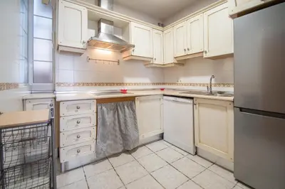 a kitchen with white cabinets and a sink and a dishwasher at Apartamento Santa M Serenity Cadiz in Cádiz