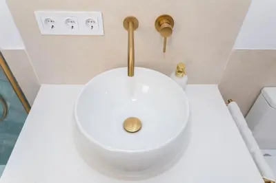 a bathroom with a white toilet with a gold handle at GINVA - Apartamento en pleno centro 3 in El Puerto de Santa María