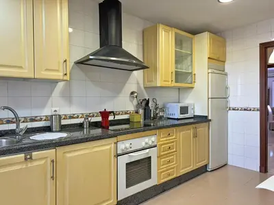 a kitchen with yellow cabinets and a stove top oven at Apartamento Minotauro - Ole Solutions in Jerez de la Frontera