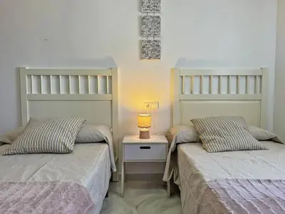 two beds in a room with a lamp on a night stand at Apartamento Minotauro - Ole Solutions in Jerez de la Frontera