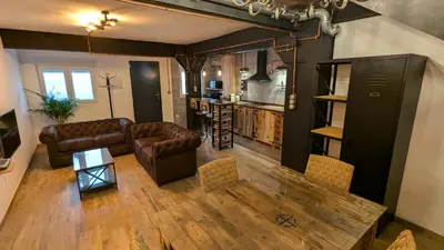 a living room with leather furniture and a kitchen at Loft Duplex La Industrial Playa in Cádiz
