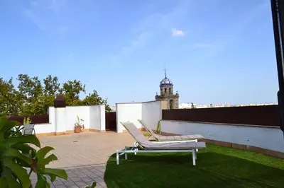 a lounge chair on a roof with a lighthouse in the background at Penthouse City Center - Jerez in Jerez de la Frontera