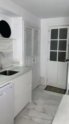 a white kitchen with a sink and a door at piso de 2 dormitorios in El Puerto de Santa María