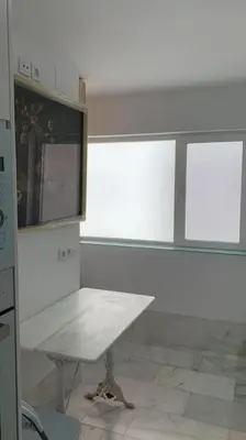 a white room with a table and a window at piso de 2 dormitorios in El Puerto de Santa María