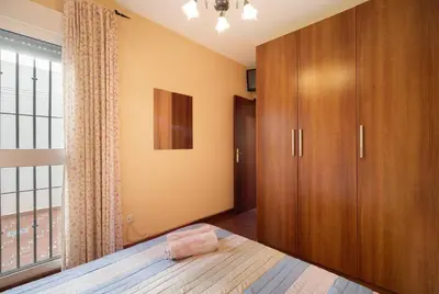 a bedroom with a bed and a large window at Apartamento Al Ándalus 43 in Chiclana de la Frontera