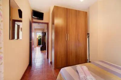 a bedroom with a bed and a wooden cabinet at Apartamento Al Ándalus 43 in Chiclana de la Frontera
