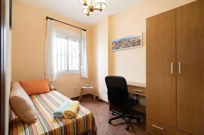 a bedroom with a desk and a bed and a chair at Apartamento Al Ándalus 43 in Chiclana de la Frontera