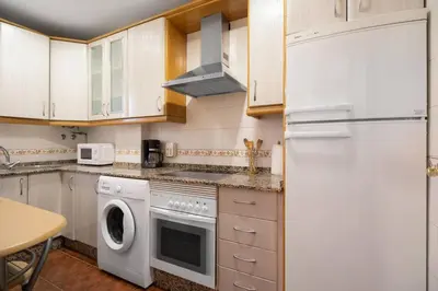 a kitchen with a white refrigerator and a dishwasher at Apartamento Al Ándalus 43 in Chiclana de la Frontera