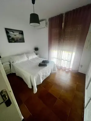 a bedroom with a white bed and a wooden floor at Casa 3 dormitorios La Barrosa in Chiclana de la Frontera