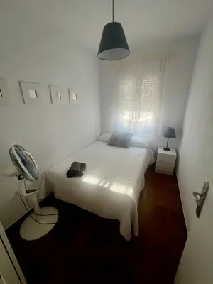 a small bedroom with a white bed and a window at Casa 3 dormitorios La Barrosa in Chiclana de la Frontera