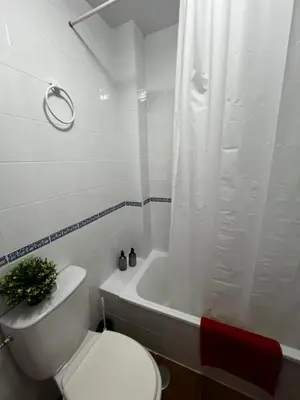 a white bathroom with a toilet and a bath tub at Casa 3 dormitorios La Barrosa in Chiclana de la Frontera