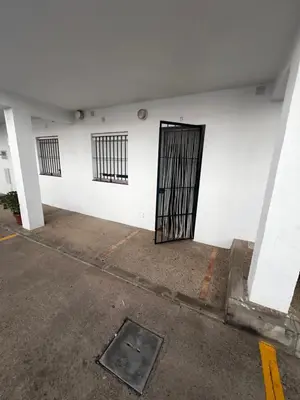 a white wall with a gate in a parking lot at Casa 3 dormitorios La Barrosa in Chiclana de la Frontera
