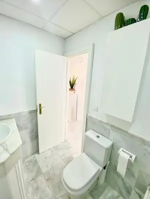 a white bathroom with a toilet and a sink at Apartamento Atlántico in Rota
