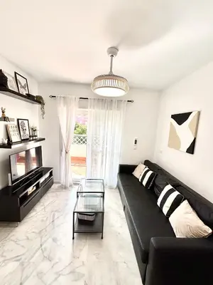 a living room with a black couch and a glass table at Apartamento Atlántico in Rota