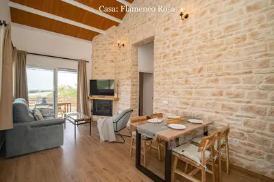 a living room with a table and a brick wall at Casa Rural Mirador del Guadalquivir-Refugio con Piscina y Chimenea in Trebujena