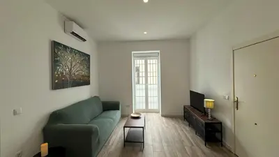 a living room with a green couch and a television at Sibs Sanlúcar Lucero Edificio Unico Terraza Tranquilo in Sanlúcar de Barrameda