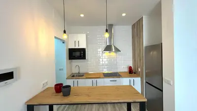a kitchen with a wooden table and a refrigerator at Sibs Sanlúcar Lucero Edificio Unico Terraza Tranquilo in Sanlúcar de Barrameda