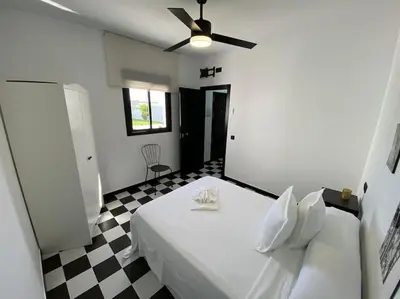 a bedroom with a white bed with a ceiling fan at Villa con piscina Camino Doñana in Sanlúcar de Barrameda