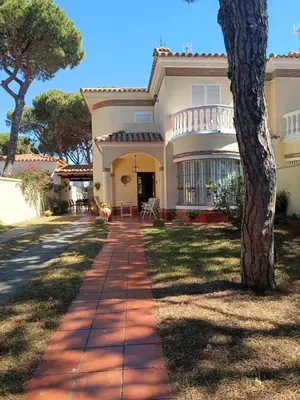 a house with a tree in front of a sidewalk at Casa Mar Baltico a 200 m de la Playa La Barrosa in Chiclana de la Frontera