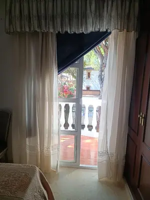 a bedroom with a large window with white curtains at Casa Mar Baltico a 200 m de la Playa La Barrosa in Chiclana de la Frontera