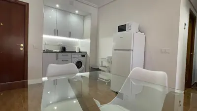 a kitchen with a glass table with chairs and a refrigerator at Bahia Sur Deluxe in San Fernando