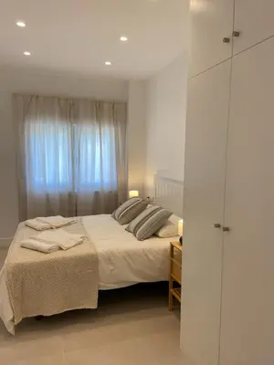 a white bedroom with a bed and a window at Apartamentos a estrenar de dos dormitorios in San Fernando