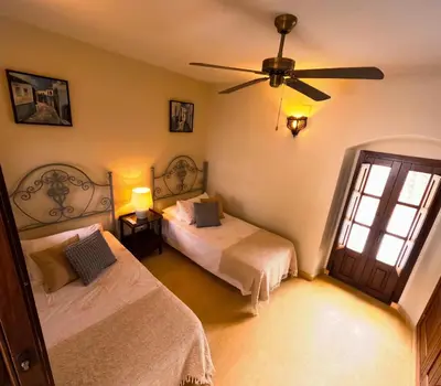 a bedroom with two beds and a ceiling fan at Casa de Medina in Medina Sidonia