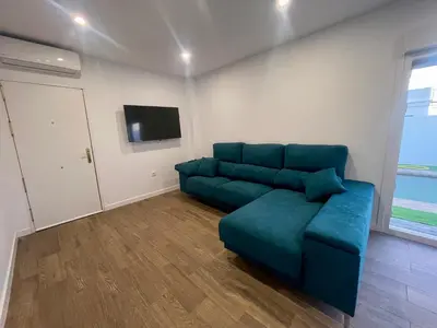 a living room with a blue couch and a tv at Preciosa casa Sol y Luna in Chiclana de la Frontera