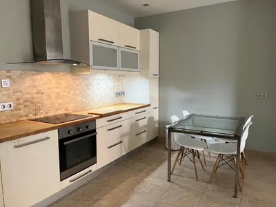 a kitchen with white cabinets and a glass table at Mi Teja in Chiclana de la Frontera
