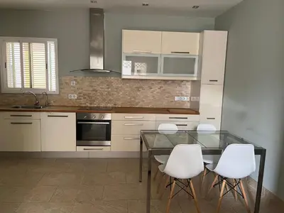 a kitchen with a glass table and white chairs at Mi Teja in Chiclana de la Frontera