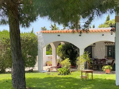 a white building with an archway and a table and bench at Campito cerca del mar 