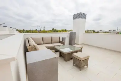 a living room with a couch and a table on a balcony at Luxury Beach Townhouse Retreat in Cádiz