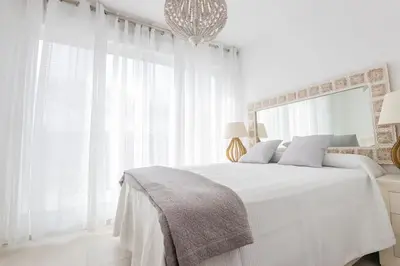 a white bedroom with a large bed with white curtains at Luxury Beach Townhouse Retreat in Cádiz
