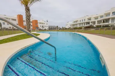 a swimming pool with blue water in a resort at Luxury Beach Townhouse Retreat in Cádiz