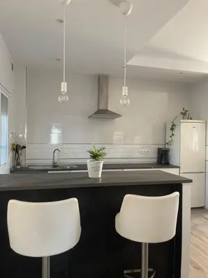 a kitchen with two white chairs at a counter at La casa de Cris in Sanlúcar de Barrameda